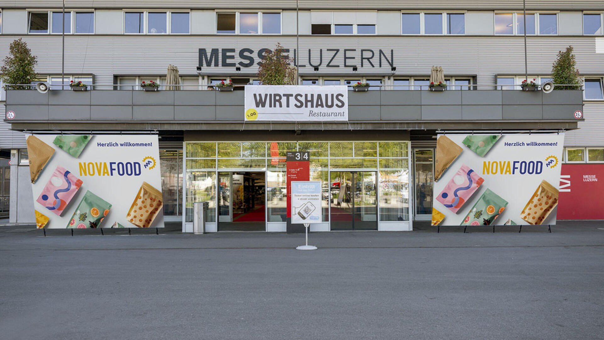 Der Eingang der Messe Luzern, geschmückt mit grossen Bannern für NOVA FOOD und einem Wirtshaus-Schild über den Türen, das die Besucher zur Veranstaltung willkommen heisst.