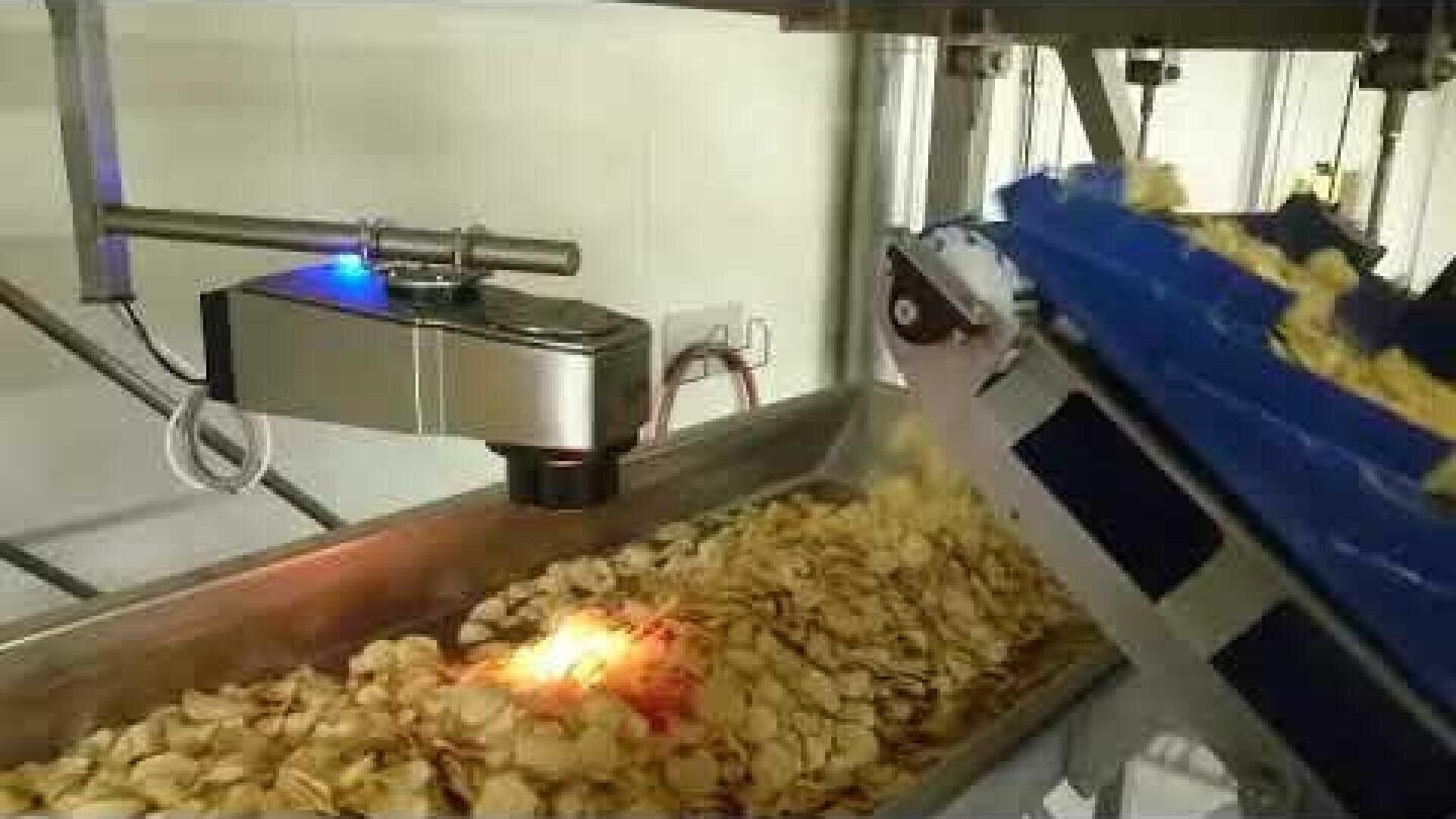 Automatisches Qualitätskontrollsystem, das mithilfe eines Sensors und Förderbänder Kartoffelchips während ihres Transports durch eine Lebensmittelverarbeitungsanlage prüft.