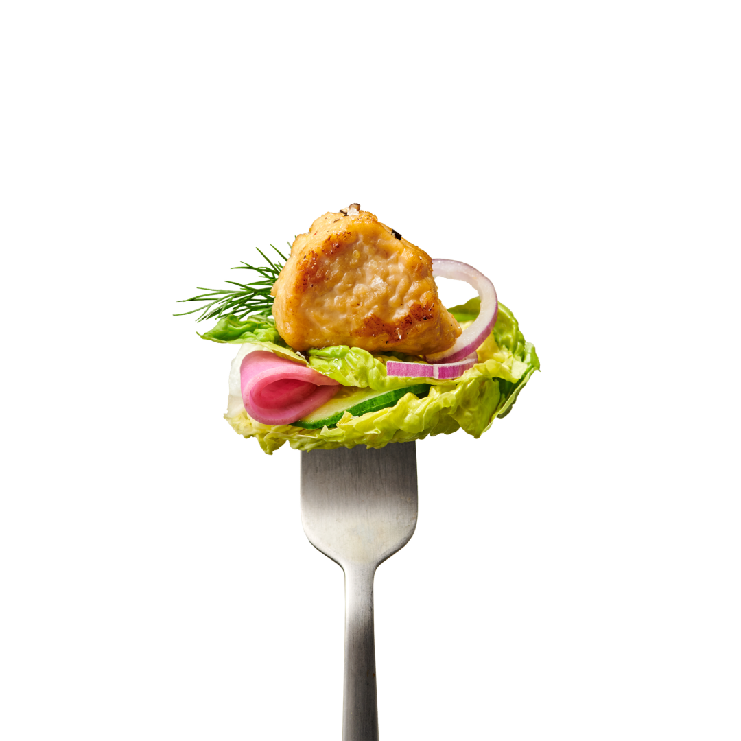 Eine Gabel, auf der ein Salatblatt mit einem Stück gegartem Fleisch, einer Scheibe roter Zwiebel, Gurke und einem Dillzweig liegt.