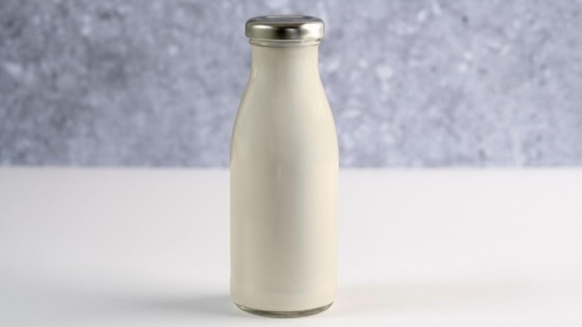 Eine Glasflasche, gefüllt mit Milch und mit einem silbernen Deckel verschlossen.