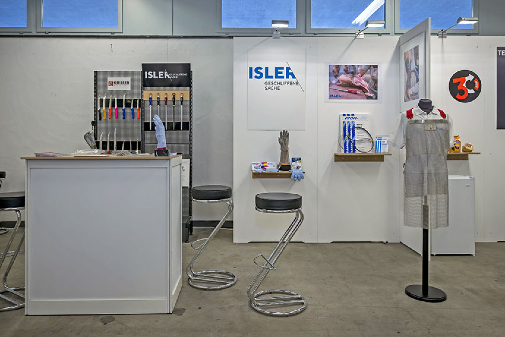 Messestand für Isler mit Ausstellungsstücken wie Profimessern, Schutzhandschuhen und einer Kettenhemd-Schürze.